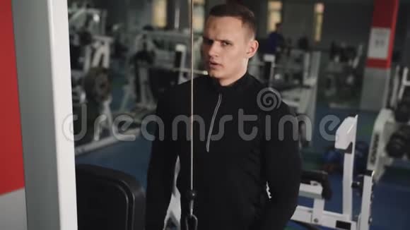 肌肉男在健身房锻炼时做缆绳肱三头肌向下推运动视频的预览图