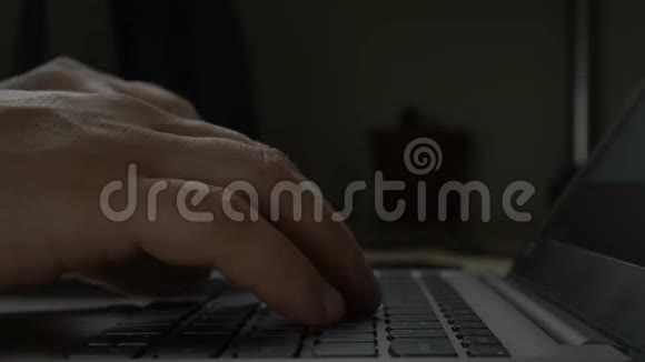 夜晚黑暗中男人用手在笔记本电脑键盘上打字视频的预览图