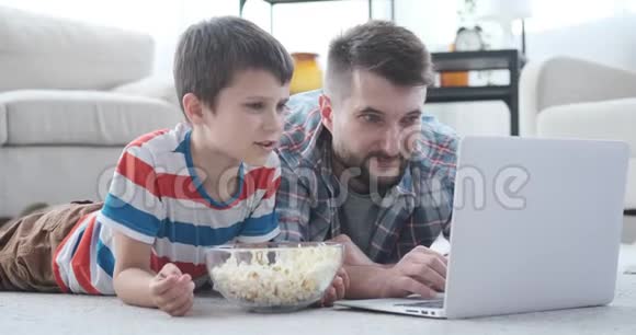 父子俩在笔记本电脑上看电影视频的预览图