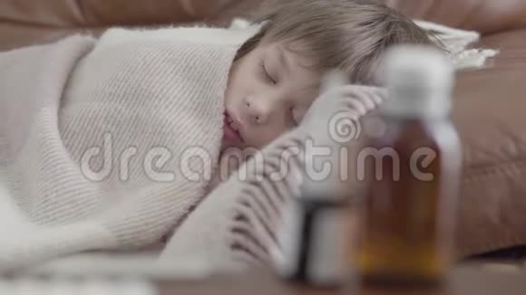肖像小男孩躺在沙发上家里盖着一条毯子可爱的孩子在休息患病儿童的概念视频的预览图