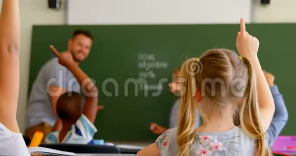 一群学生坐在课桌前在学校的教室里举手视频的预览图