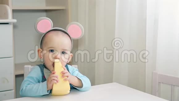 一个穿着灰色老鼠服装的小孩咀嚼着黄色奶酪里面有洞视频的预览图