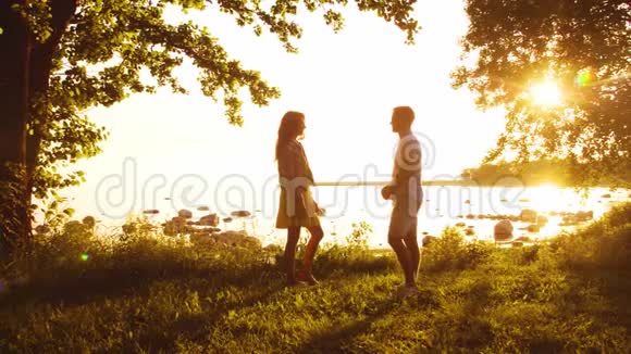 幸福的一家人走在海边农村的田野和树木日落或日出的暖色有爱心的父母视频的预览图