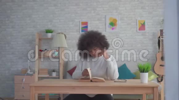 非洲裔美国妇女发型是非洲的在桌旁看书视频的预览图
