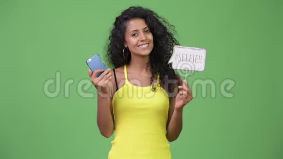年轻漂亮的西班牙女人拿着电话和自拍纸标志视频的预览图