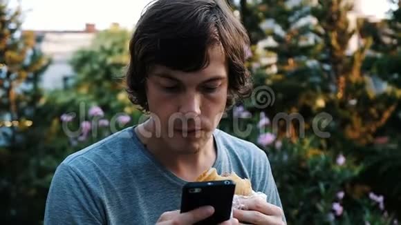 对电话和互联网的依赖一个男人正在使用智能手机吃带有奶酪的卡查普里面包视频的预览图