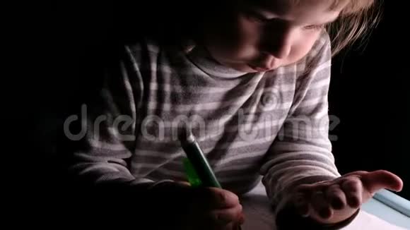 小女孩学会在家里用记号笔和铅笔在黑暗中的一张纸上画画视频的预览图