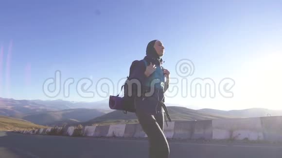 年轻的阿拉伯女人带着旅游背包在群山的背景下沿着山路旅行慢悠悠视频的预览图