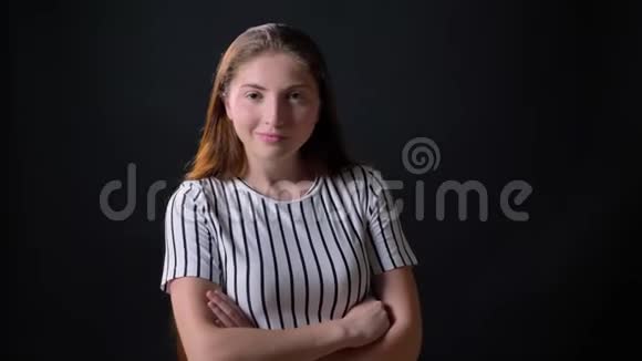 自信的年轻女子穿着条纹衬衫对着镜头微笑双手交叉站在黑色背景上视频的预览图