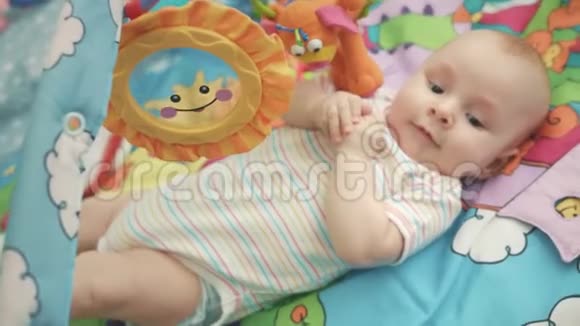 快乐的婴儿躺在五颜六色的垫子上快乐的婴儿玩耍视频的预览图