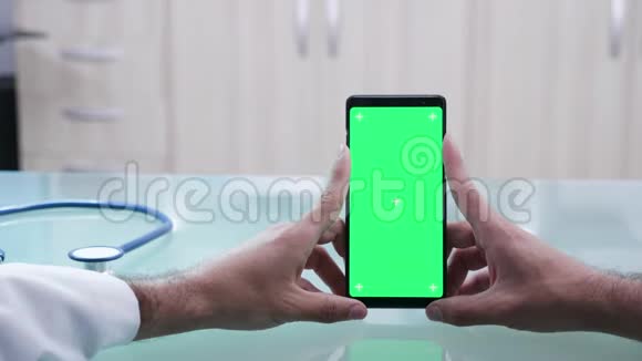 双手握着绿色屏幕的智能手机近距离拍摄视频的预览图