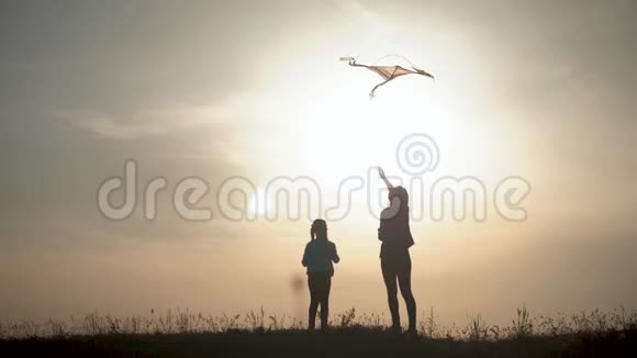 幸福的家庭母女在日落时分在草地上放风筝有趣的家庭时光友好家庭的概念视频的预览图