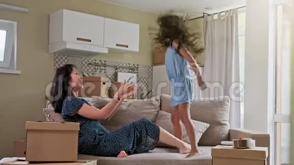 年轻的母亲和她的小女儿跳上了床有趣的枕头大战一起玩享受当下家庭时间视频的预览图