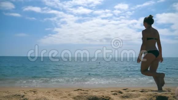 一个面目全非的年轻女子在沙滩上向大海跑去举起手来美丽的女孩在沙滩上慢跑到视频的预览图