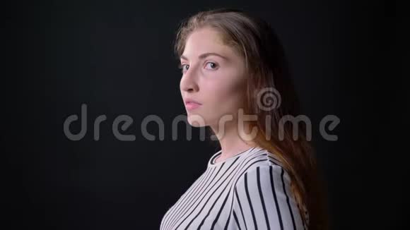 年轻焦虑的女人转过头看着摄像机站在黑色背景上严肃而自信视频的预览图