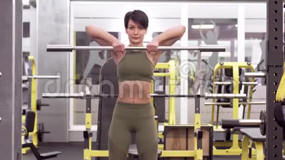 美丽的黑发女人用杠铃训练肩部肌肉视频的预览图