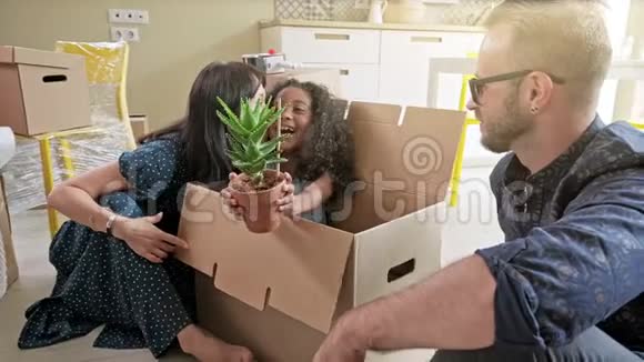 幸福混血儿家庭打开拆箱纸箱包裹讨论搬迁后的室内设计装饰视频的预览图