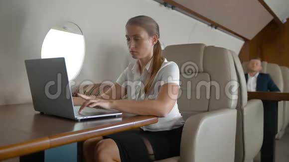 在飞机上使用现代智能手机和笔记本电脑的年轻女性肖像视频的预览图