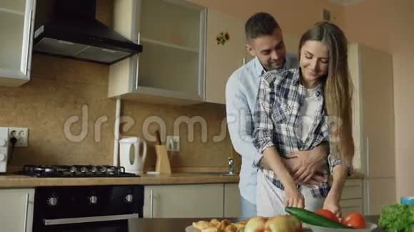 快乐的年轻夫妇在厨房漂亮的烹饪女人早上喂她男朋友视频的预览图