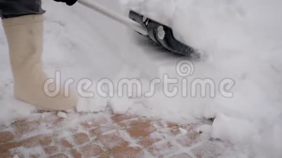 雪后用铲子清理雪道的人的特写视频的预览图