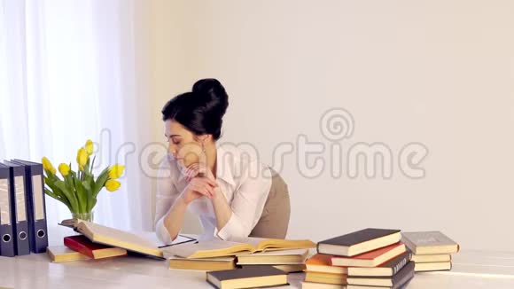 工作太累了困倦的年轻女人坐在书桌前拿书视频的预览图