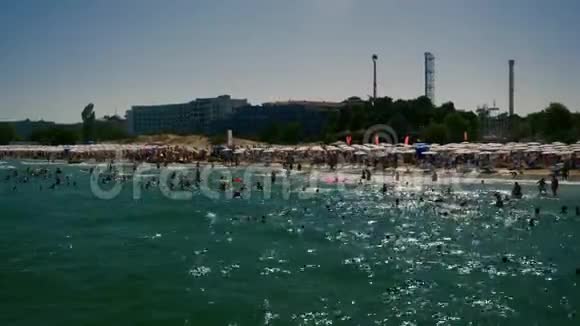 拥挤的海滩上到处都是人们的日光浴床和雨伞视频的预览图