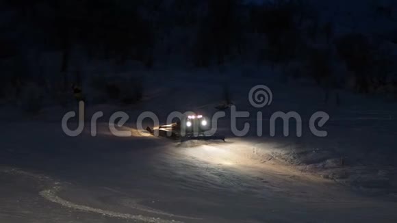 雪猫雪犁在黑夜中移动着雪头灯亮着视频的预览图