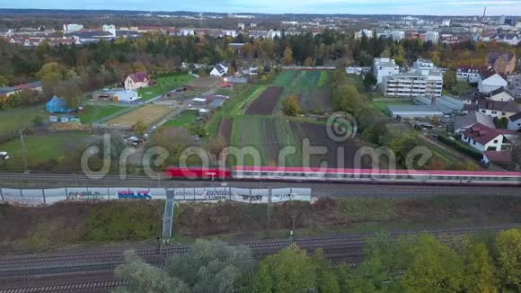 一辆红色的客运列车穿过奥格斯堡的绿色郊区视频的预览图