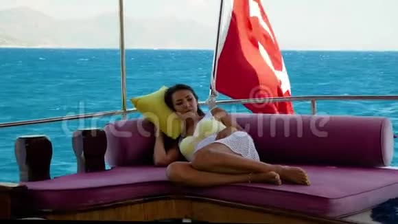 夏日里美丽的女孩躺在游艇上的沙发上视频的预览图