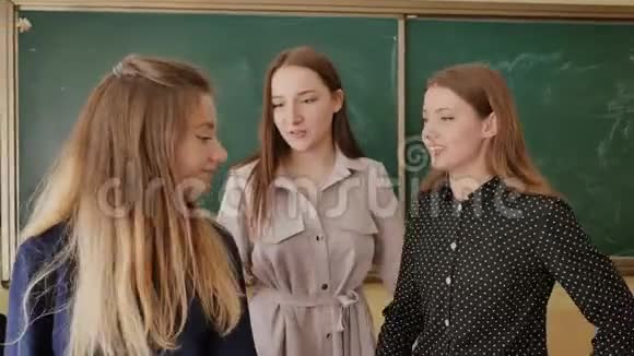 三个女学生正对着一个学校董事会的背景镜头摆姿势视频的预览图