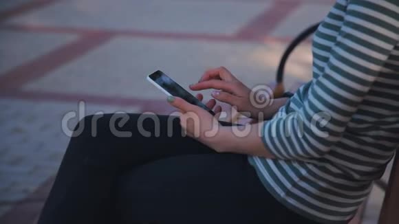 在公园里坐在长凳上用手机的年轻女子视频的预览图