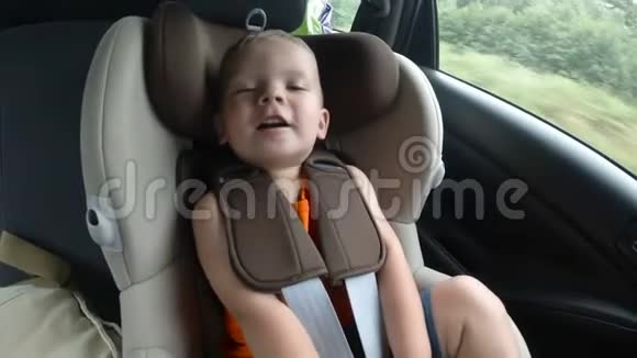 孩子们的小男孩汽车座椅在车上孩子笑着笑着高兴地挥动他的手视频的预览图