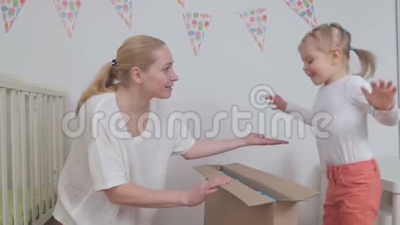 妈妈和女儿为一个孩子打开一个新买的大纸盒视频的预览图