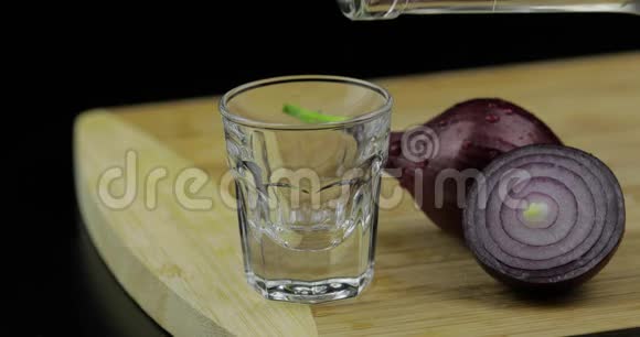 把酒精伏特加从瓶中倒入盛有洋葱的切块玻璃视频的预览图