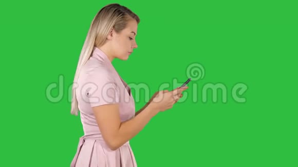 漂亮的女人穿着粉红色的连衣裙在绿色屏幕上的智能手机上发短信Chroma键视频的预览图