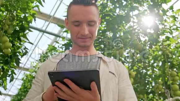在温室里使用或玩平板电脑的年轻人绿色植物生长在温暖的房子里视频的预览图