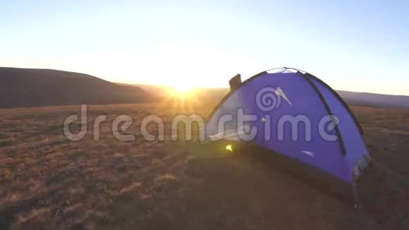 年轻的野营妇女双手张开在日落时分从帐篷里出来视频的预览图