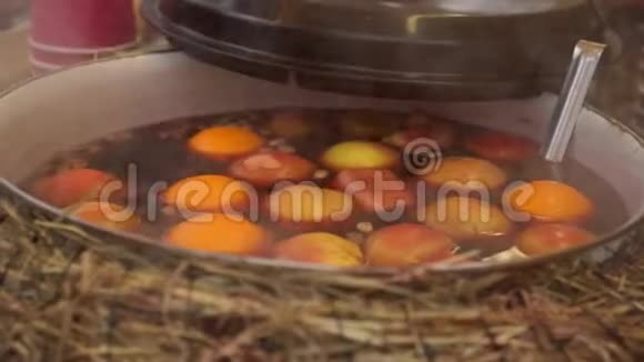 在装有苹果和橘子的平底锅中搅拌葡萄酒热饮水果饮料美食集市街头美食视频的预览图