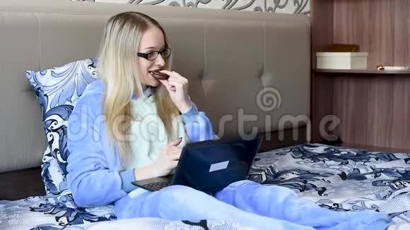 女孩们早上在床上吃甜点看着笔记本电脑视频的预览图