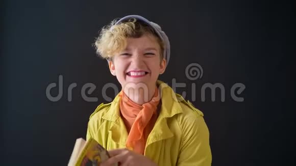 穿着黄色夹克的漂亮快乐的女人在黑色背景下学习法语在镜头前微笑视频的预览图