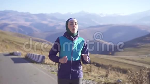 戴头巾的阿拉伯女人在太阳山公路上跑回山景视频的预览图