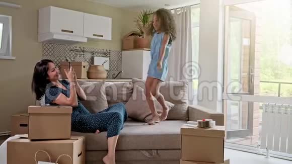 年轻的母亲和她的小女儿跳上了床有趣的枕头大战一起玩享受当下家庭时间视频的预览图