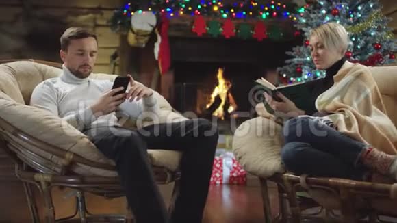 丈夫使用智能手机而妻子则在圣诞夜看书视频的预览图