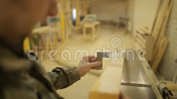 木工车间的一名工人用一个方形的特写的加工的锯木机检查板的角度视频的预览图