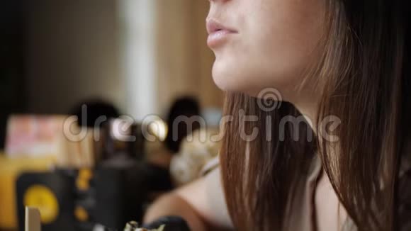 把戴黑手套的年轻女孩关起来在咖啡馆里吃一个多汁的汉堡视频的预览图