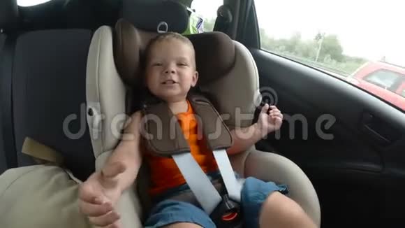 孩子们的小男孩汽车座椅在车上孩子笑着笑着高兴地挥动他的手视频的预览图