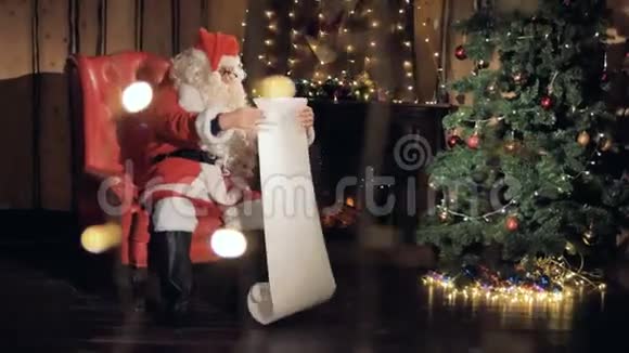 圣诞前夜圣诞快乐的圣诞老人在壁炉边念礼物清单4K视频的预览图