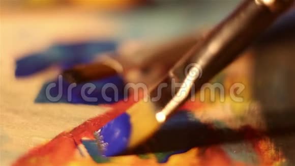 艺术家用蓝色颜料将画笔浸入调色板上视频的预览图