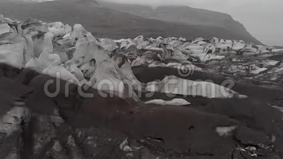 空中俯视白色冰川山脊与黑色灰烬冰岛国家公园的风景冰山视频的预览图