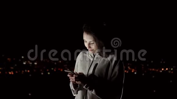 美丽的女孩晚上在夜城的背景上使用电话慢莫视频的预览图